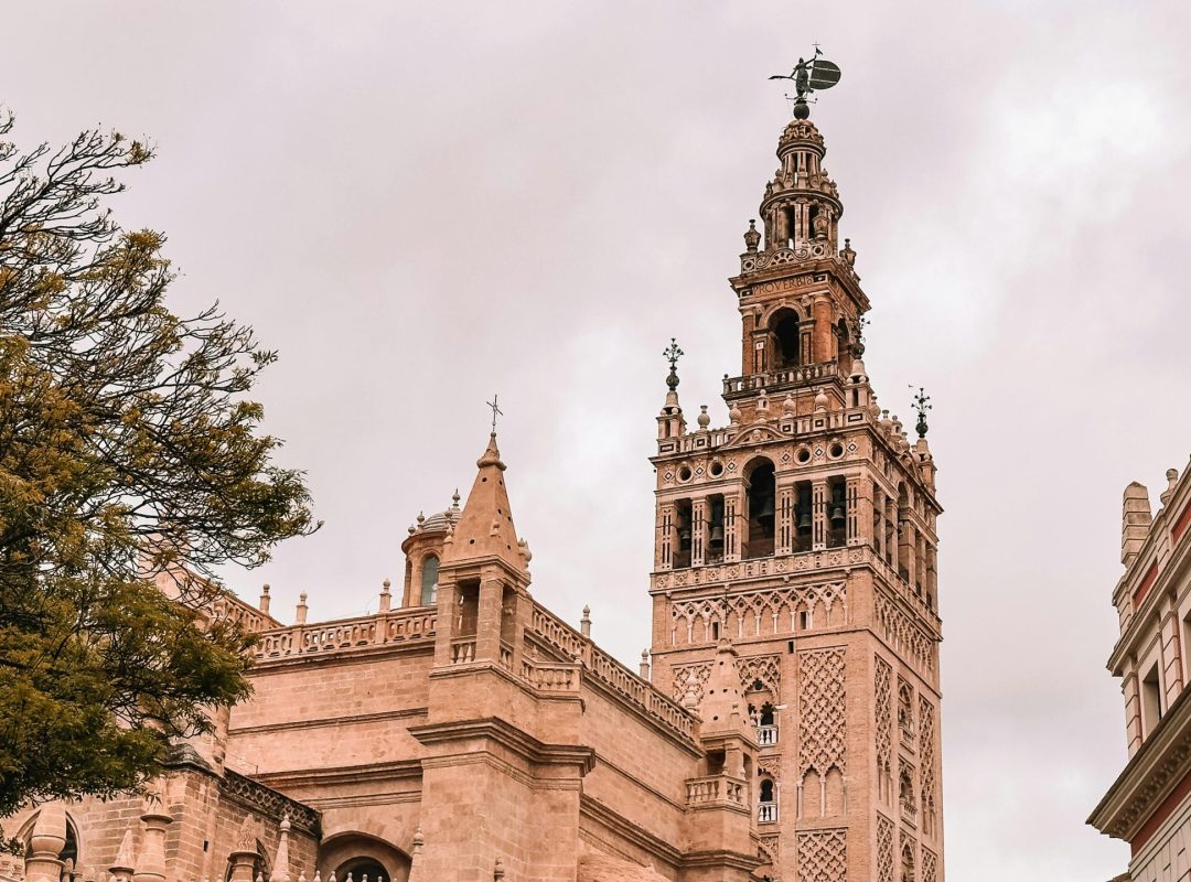 A striking view of the Giralda Tower against a cloudy sky in Sevilla, Spain.