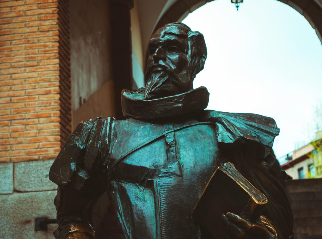 Bronze statue depicting Don Quixote, set under an archway in Toledo, Spain.